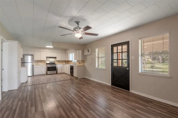 a living room with stainless steel appliances kitchen island granite countertop a stove a refrigerator cabinets and wooden floor