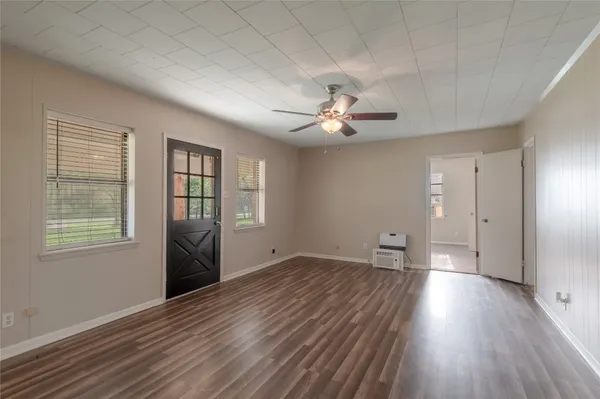 an empty room with wooden floor and windows