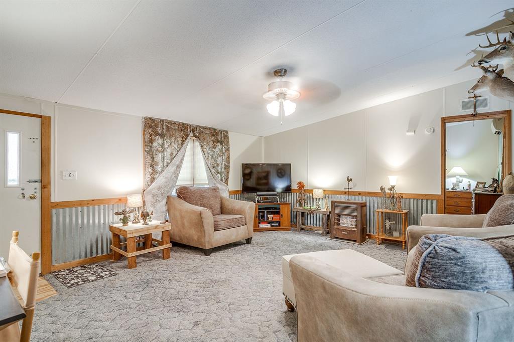 436 Luke Road Springtown, TX 76082 - Photo 12 of 39 Carpeted living area with a wainscoted wall, lofted ceiling, and a ceiling fan