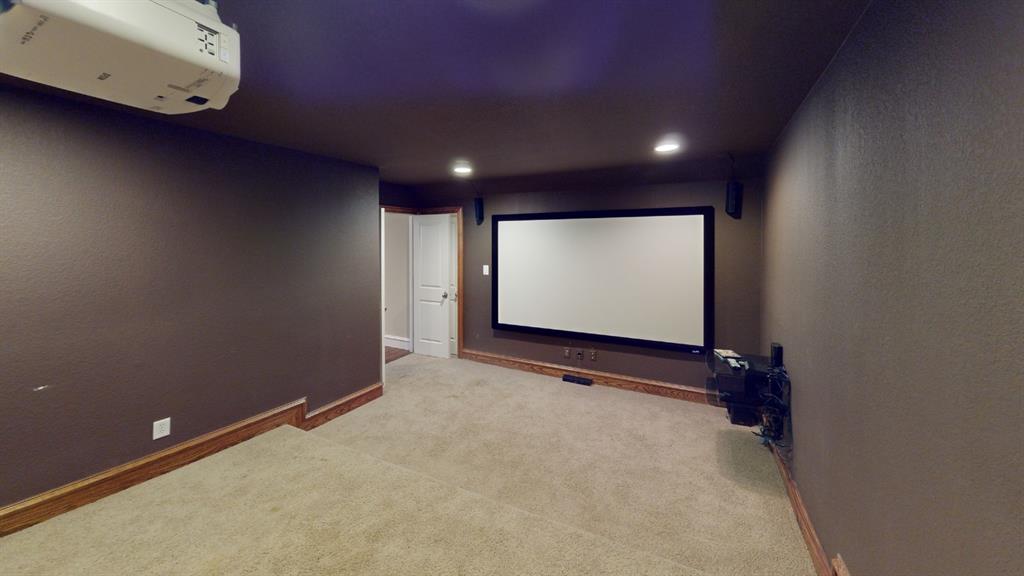 4516 Gilbert Avenue Dallas, TX 75219 - Photo 16 of 28 Dedicated entertainment space featuring a large projection screen, integrated speakers, and a ceiling-mounted projector