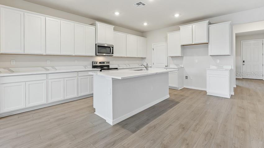 1925 Cobb Trail Parrish, FL 34219 - Photo 4 of 25 a kitchen with stainless steel appliances granite countertop a white cabinets a sink a stove a refrigerator and white cabinets