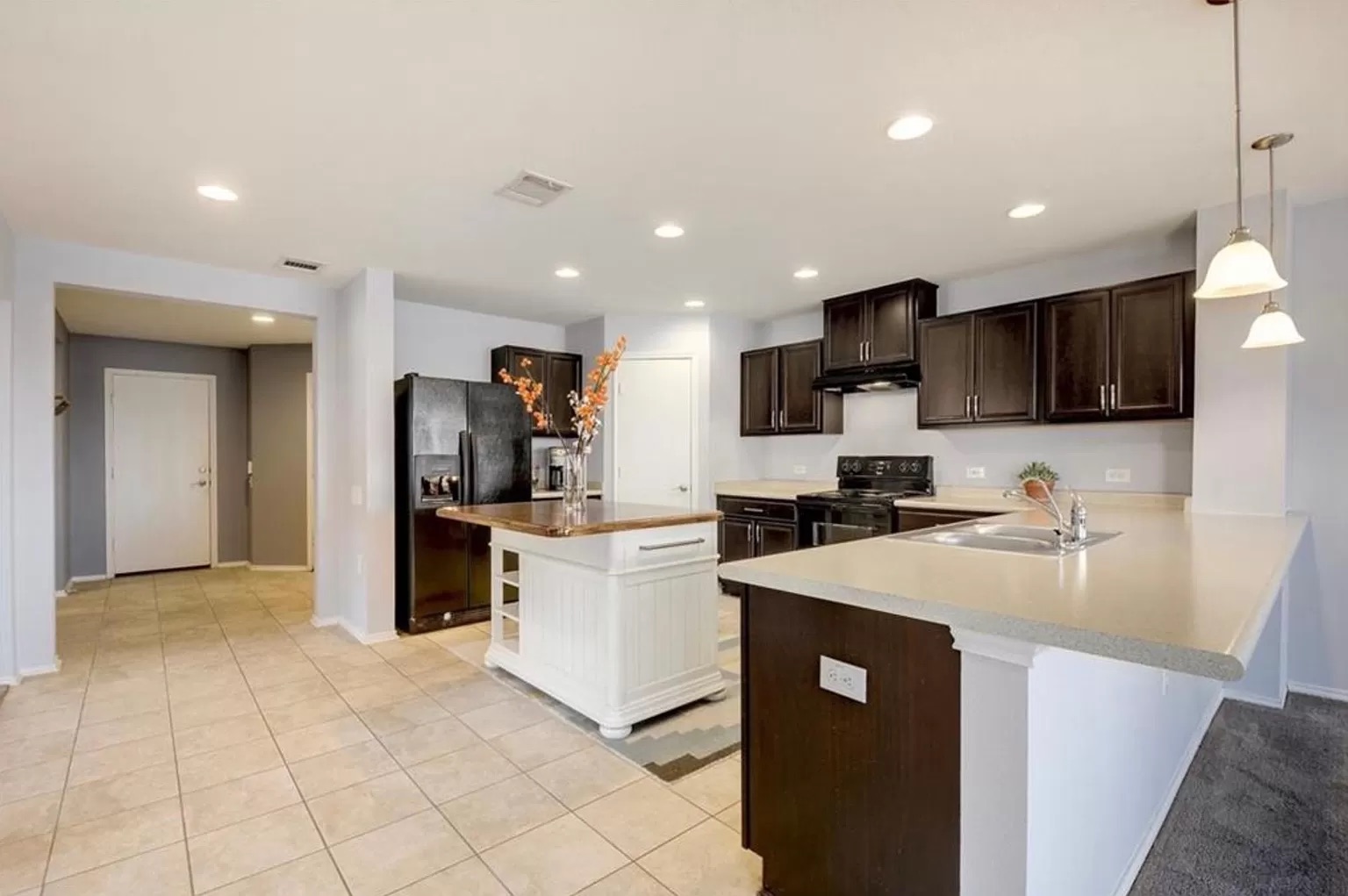 9016 Ridgewell Road Austin, TX 78747 - Photo 6 of 30 A well-lit kitchen with dark cabinetry, ample counter space, and a functional island.
