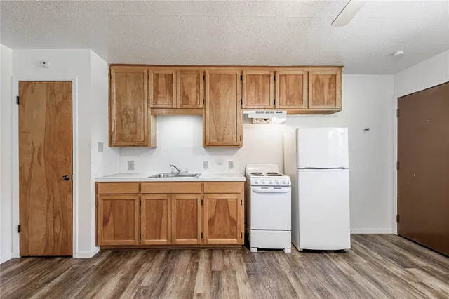 a kitchen with stainless steel appliances granite countertop a refrigerator a stove and a wooden floors