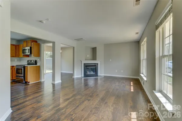an empty room with wooden floor fireplace and windows
