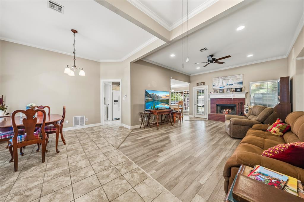 10127 Cougar Ridge Parkway Waco, TX 76708 - Photo 21 of 33 Open concept living space featuring wood-finish flooring, a brick fireplace with a white mantel, and a ceiling fan