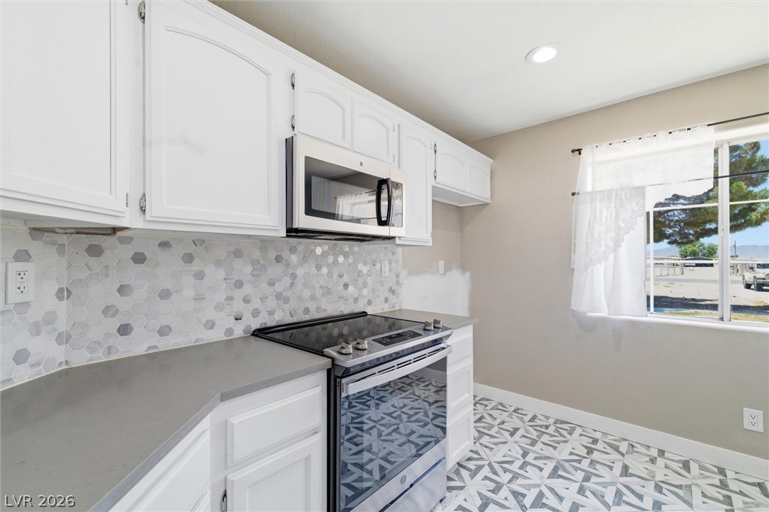2780 West Simkins Road Pahrump, NV 89060 - Photo 16 of 40 Culinary comfort awaits with a stainless steel range and microwave, complemented by patterned flooring and ample cabinetry.
