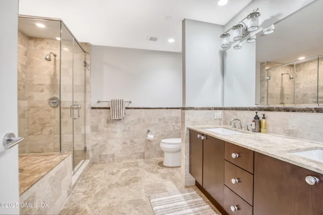 a bathroom with a double vanity sink toilet and shower