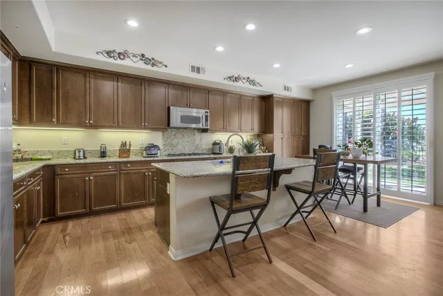 a kitchen with stainless steel appliances kitchen island granite countertop a stove a sink a dining table and chairs