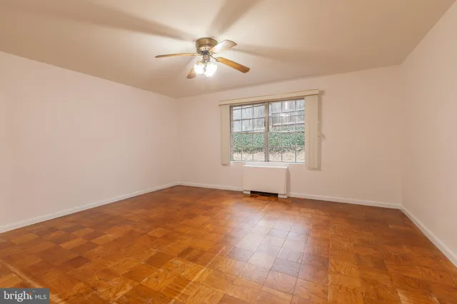 an empty room with chandelier fan and windows