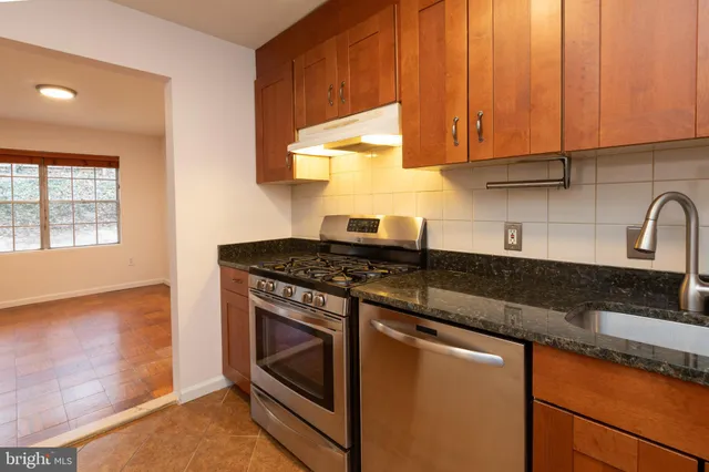 a kitchen with granite countertop wooden cabinets and a stove top oven