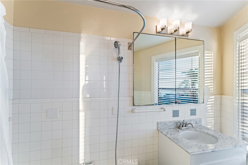 770 Hillcrest Drive, Unit 7 Laguna Beach, CA 92651 - Photo 17 of 30 a bathroom with a granite countertop sink a mirror and a shower