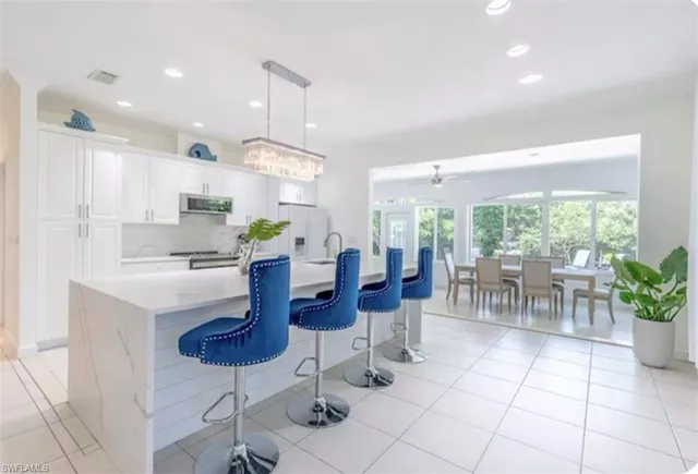 a kitchen with stainless steel appliances kitchen island granite countertop a refrigerator a stove a sink with a dining table and chairs