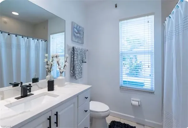 a bathroom with a granite countertop sink toilet and a mirror