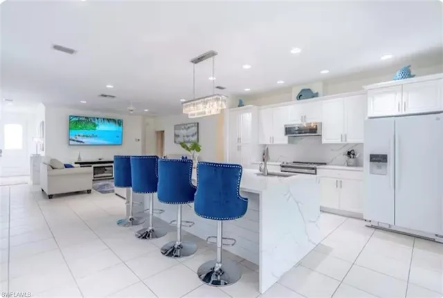 a kitchen with stainless steel appliances kitchen island granite countertop a refrigerator and a sink