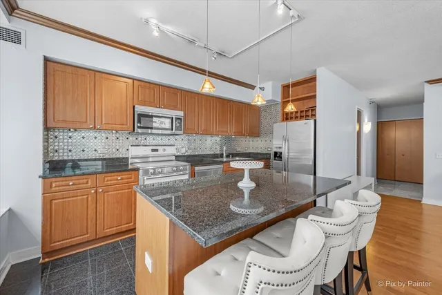 a kitchen with stainless steel appliances granite countertop a sink a stove and a refrigerator