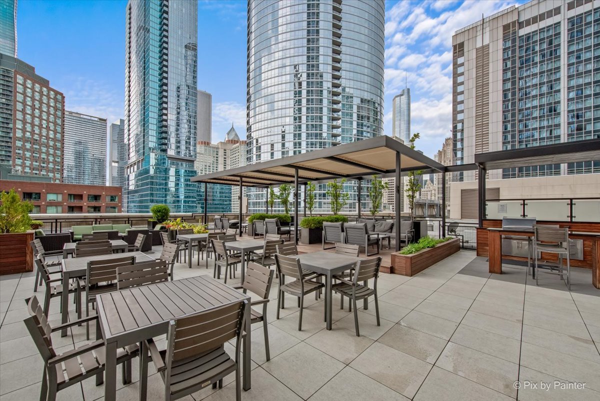 512 North McClurg Court, Unit 501 Chicago, IL 60611 - Photo 30 of 40 a view of a patio with dining table and chairs under an umbrella with a barbeque