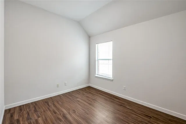 an empty room with wooden floor and window