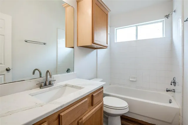 a bathroom with a granite countertop sink a toilet and bathtub