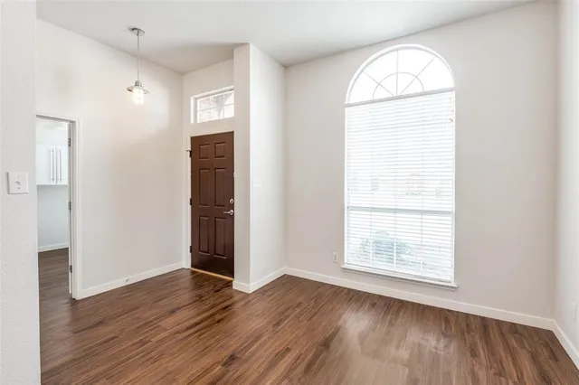 an empty room with wooden floor cabinet and windows