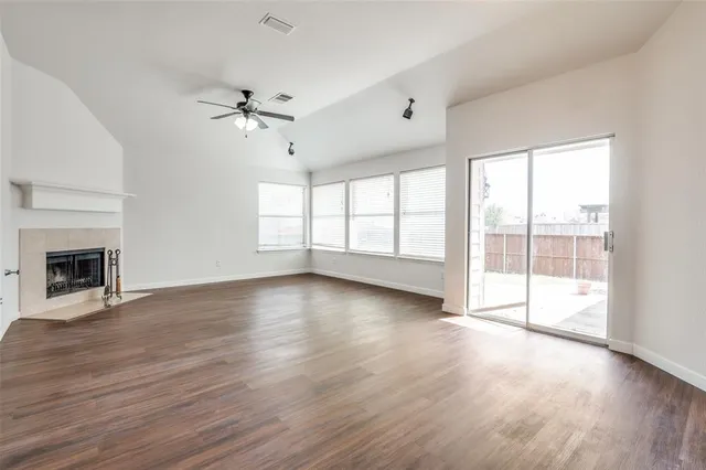 an empty room with wooden floor fireplace and windows