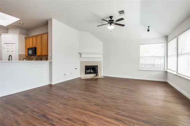 a view of an empty room with a window and wooden floor
