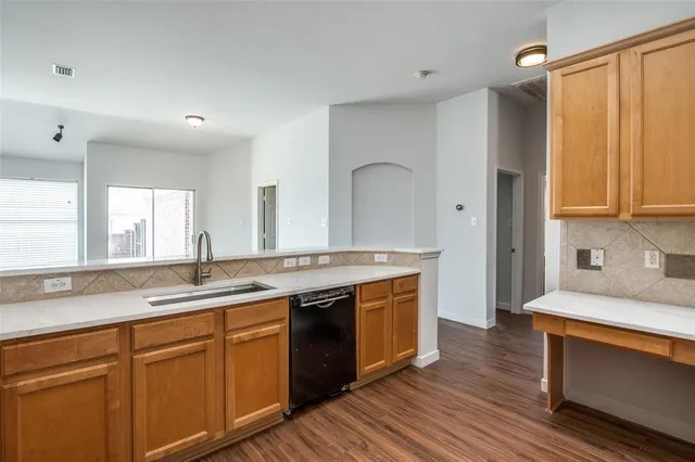 a view of a kitchen counter space a sink wooden floor and stainless steel appliances
