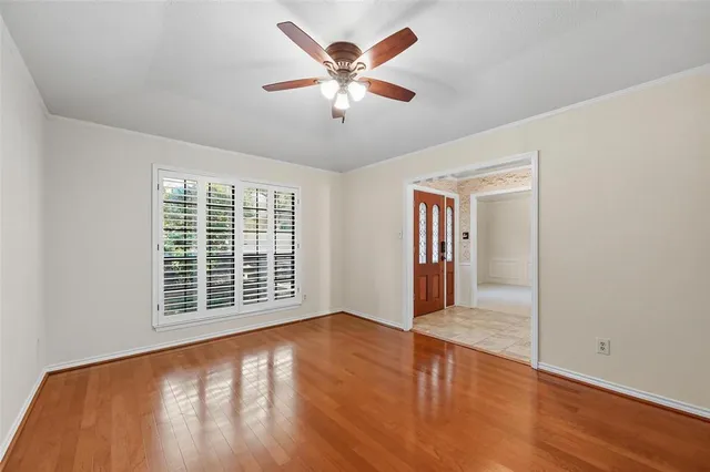 a view of an empty room with a window and wooden floor