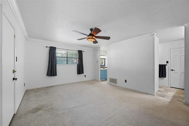 an empty room with chandelier fan and windows