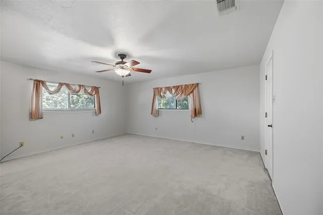 an empty room with windows and ceiling fan