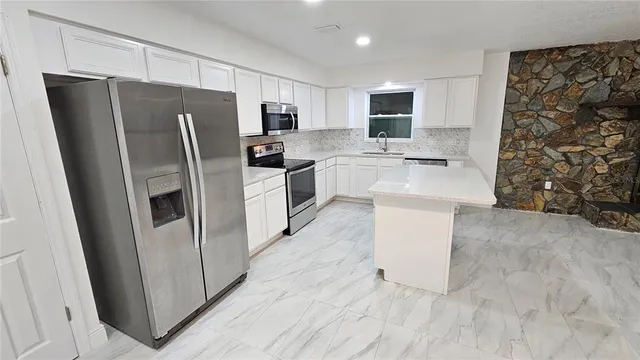 a view of an empty room with wooden floor and a fireplace