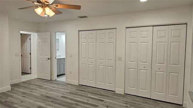an empty room with wooden floor chandelier fan and windows