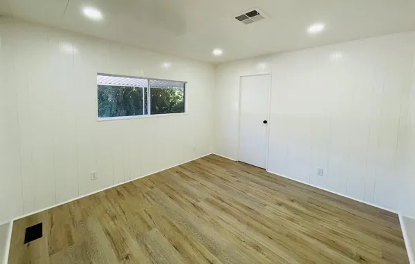 a view of empty room with wooden floor and fan