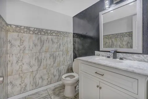 a bathroom with a granite countertop bathtub sink vanity mirror and toilet