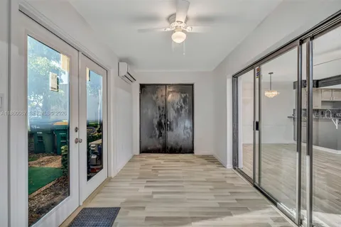 a view of a hallway with a chandelier fan and glass door