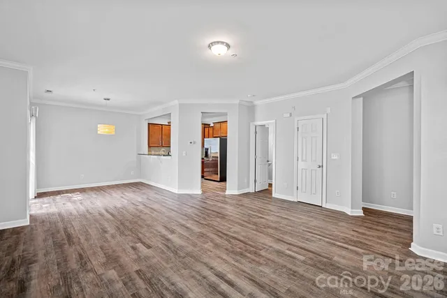 a view of an empty room with wooden floor and closet