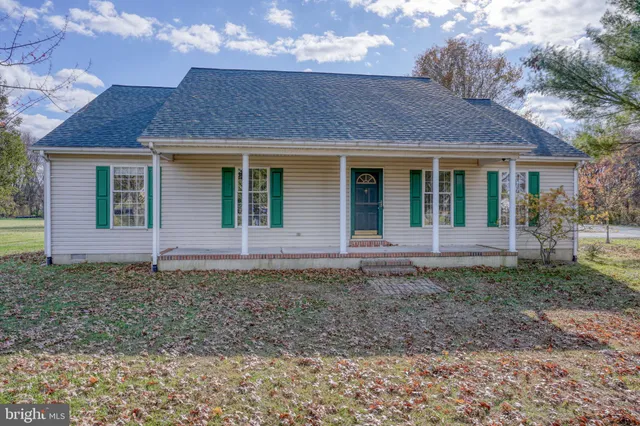 a view of a brick house with yard and a large tree