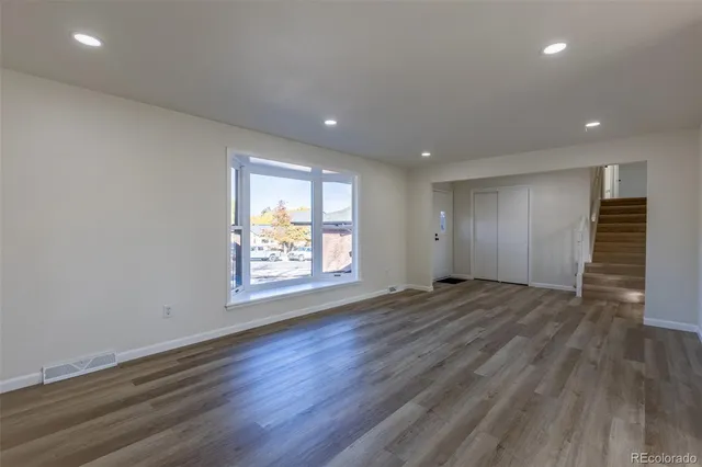 an empty room with wooden floor and window