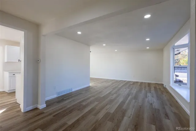 a view of an empty room with wooden floor and a window