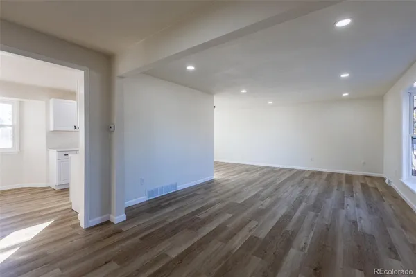 an empty room with wooden floor & windows