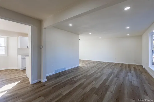 an empty room with wooden floor & windows