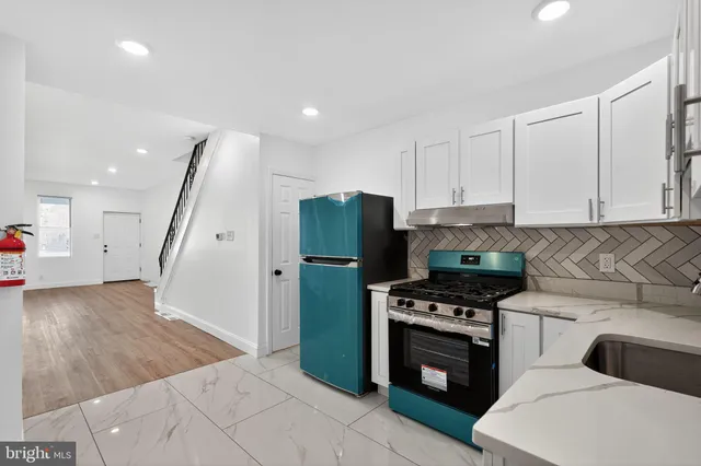a kitchen with granite countertop a refrigerator and a stove top oven
