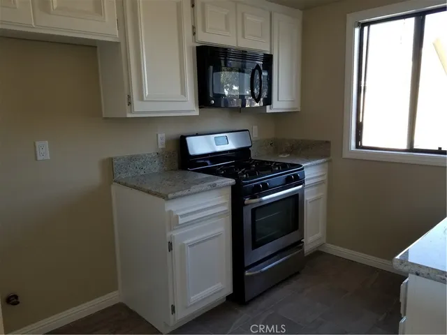 a kitchen with granite countertop white cabinets and black appliances
