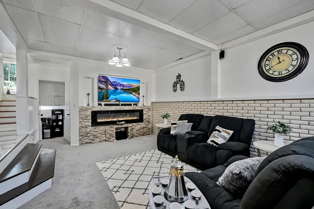 a living room with furniture a clock on wall and a flat screen tv