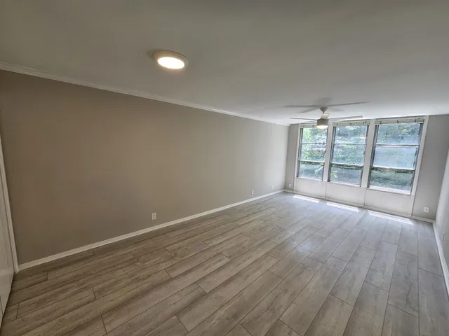 an empty room with wooden floor and a ceiling fan