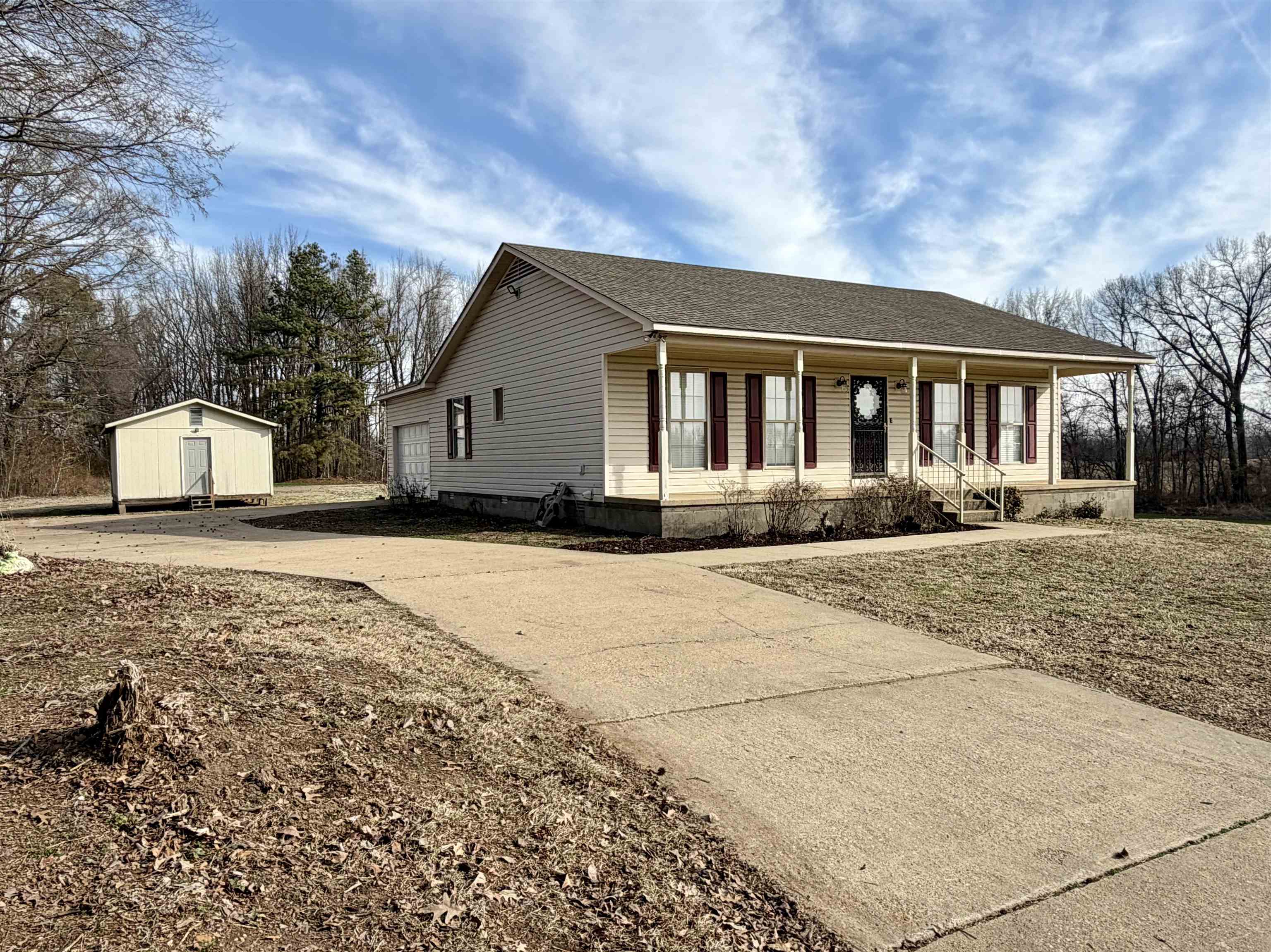 1086 Sloan Road Burlison, TN 38015 - Photo 2 of 24 View of front of home with a porch, concrete driveway, roof with shingles, a storage unit, and a garage