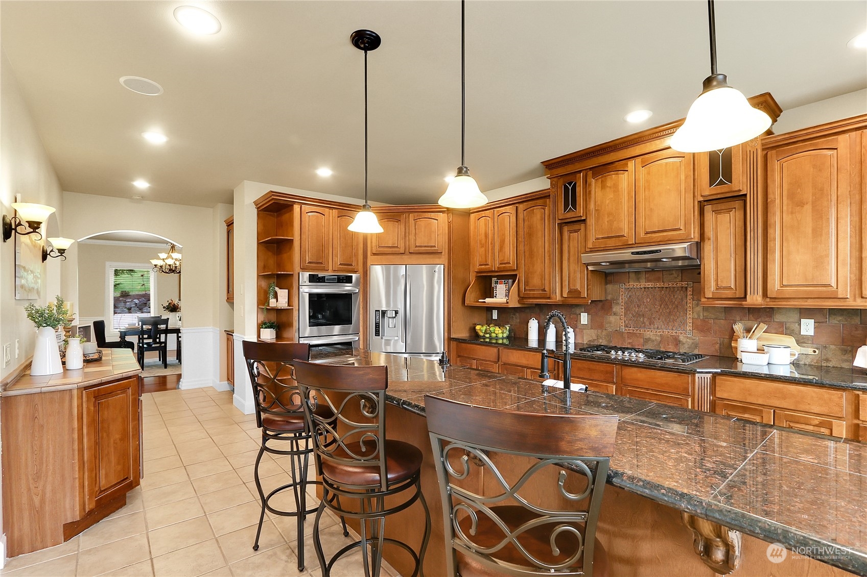 13921 Jim Creek Road Arlington, WA 98223 - Photo 5 of 35 a kitchen with stainless steel appliances granite countertop a stove a sink a dining table and chairs with wooden floor