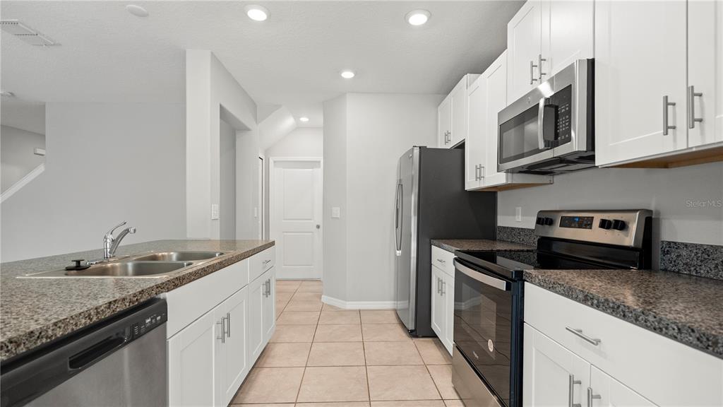7231 Spring Snowflake Avenue Tampa, FL 33619 - Photo 12 of 46 a kitchen with stainless steel appliances granite countertop a sink a stove and a refrigerator