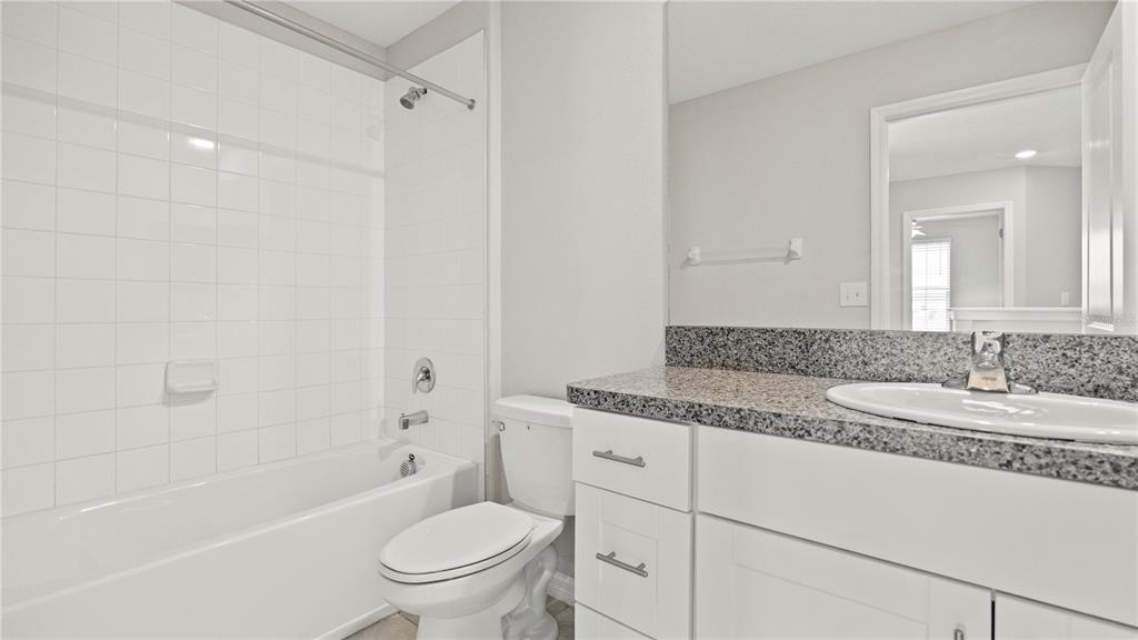 7231 Spring Snowflake Avenue Tampa, FL 33619 - Photo 33 of 46 a bathroom with a granite countertop sink a toilet and a bathtub