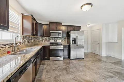a kitchen with stainless steel appliances granite countertop a refrigerator stove and sink