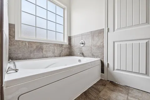 a bathroom with a bathtub and next to a window